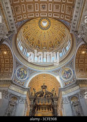 Die reich verzierte, vergoldete Kuppel und Decke des Petersdoms sind mit goldenen Sonnenstrahlen dekoriert und mit komplexen Mosaiken und Gemälden dekoriert. Luxuriös Stockfoto