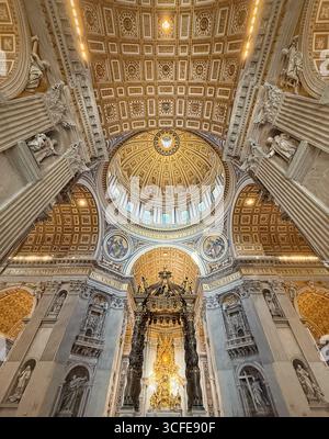 Die reich verzierte, vergoldete Kuppel und Decke des Petersdoms sind mit goldenen Sonnenstrahlen dekoriert und mit komplexen Mosaiken und Gemälden dekoriert. Luxuriös Stockfoto