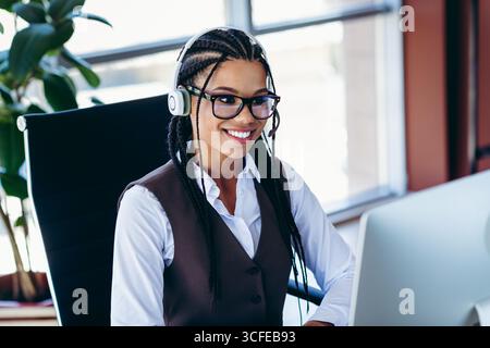 Professionelle junge Frau, die ein Headset trägt, arbeitet in einem modernen Büro mit Schwerpunkt auf Unternehmensaufgaben und Management Stockfoto