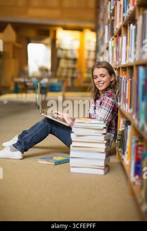 Studentinnen sitzen auf Teppichboden mit Laptop und Lehrbüchern, Kopierraum Stockfoto