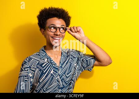 Fröhlicher junger Mann mit stilvollem gemustertem Hemd, der mit einer Brille auf einem hellgelben Hintergrund posiert Stockfoto
