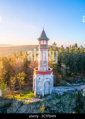 Das helle Morgenlicht des Frühlings beleuchtet den Stepanka Aussichtsturm im Isergebirge in Tschechien, umgeben von üppigen Bäumen und lebendiger Natur. Ein ruhiger Ort für Besucher. Stockfoto