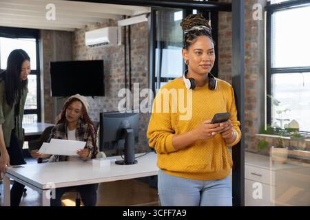 Verschiedene weibliche Kollegen arbeiten an Papieren neben dem Smartphone im Startup-Büro, im Kopierbereich Stockfoto