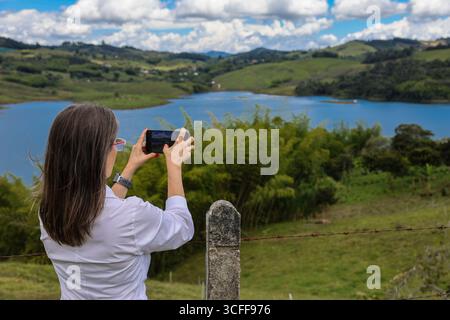 Weibliche Touristen, die Fotos am größten künstlichen See Kolumbiens machen, Calima Lake, der sich in den Bergen von Darien in der Region Valle befindet Stockfoto