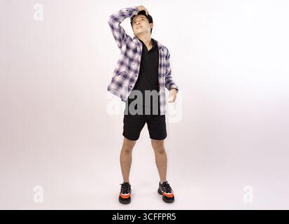 Junger Mann posiert lässig in trendigem Outfit vor einem schlichten Hintergrund Stockfoto