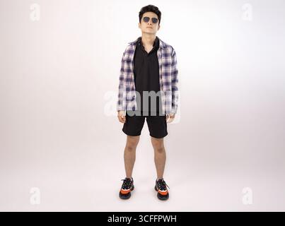 Lässiger und modischer junger Mann mit Sonnenbrille, der selbstbewusst in stilvoller Freizeitkleidung steht Stockfoto