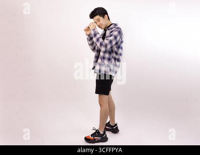 Junger Mann, der die Brille in einem lässigen Studio-Porträt passt Stockfoto