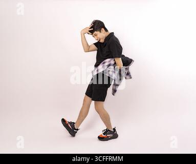 Junger Mann posiert spielerisch in kariertem Hemd mit lässigem Outfit Stockfoto
