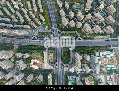 Die von oben nach unten auf eine stark frequentierte Kreuzung zeigt eine Vielzahl von Fahrzeugen, die auf verschiedenen Straßen unterwegs sind. Hangzhou, China. Stockfoto