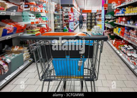 Bayern, Deutschland - 22. August 2025: Ein Einkaufswagen steht in einem Gang eines Lebensmittelmarktes. Symbolische Fotoeinkäufe, Preissteigerungen und Inflation im Lebensmitteleinzelhandel, digital aufgewertet *** ein Einkaufswagen steht in einer Gang von einem Lebensmittel Supermarkt. Symbolfoto Einkaufen, Preissteigerungen und Inflation im Lebensmitteleinzelhandel, digital nachbearbeitet Stockfoto