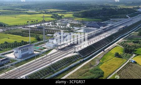 (250823) -- WUHAN, 23. August 2025 (Xinhua) -- ein Luftdrohnenfoto vom 23. August 2025 zeigt einen Testzug, der auf der Hochgeschwindigkeitsbahn Xiangyang-Jingmen in der zentralchinesischen Provinz Hubei fährt. Die Xiangyang-Jingmen Hochgeschwindigkeitsbahn nahm am Samstag den Testbetrieb auf. Die 116 km lange Eisenbahnstrecke verbindet Xiangyang in der zentralen chinesischen Provinz Hubei im Norden und Jingmen Stadt der Provinz im Süden mit einer Geschwindigkeit von 350 Kilometern pro Stunde und ist ein wichtiger Abschnitt in einer der Hauptpassagen eines größeren Hochgeschwindigkeitsbahnnetzes mit acht vertikalen Linien A Stockfoto