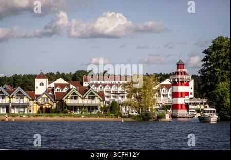 Rheinsberg: Hafen mit Hotel. - Blick auf die wasserseitige Zufahrt mit Leuchtturm und Hotel des 2008 eröffneten Hafendorfes Rheinsberg in Brandenburg. Stockfoto
