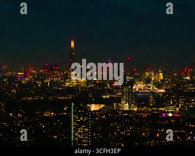 Helle Lichter der Stadt spiegeln sich von der Themse ab, während die berühmten Wahrzeichen sich vom Nachthimmel in London abheben und eine atemberaubende Atmosphäre schaffen. Stockfoto