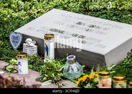 Solingen, Deutschland. August 2025. Ein Gedenkstein erinnert an die Opfer des Terroranschlags in Solingen am 23. August 2024, davor werden Kerzen und Blumen gelegt. Quelle: Christoph Reichwein/dpa/Alamy Live News Stockfoto
