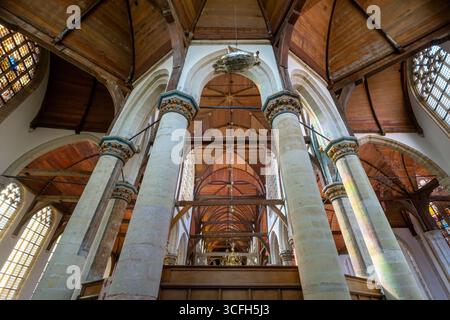Blick auf das Innere von Oude Kerk vom Presbyterium. Amsterdam. Reich bemalte Gewölbewappen von Zünften und Familien. Oude Kerk (alte Kirche) ist ein Refor Stockfoto