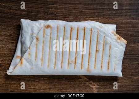 Köstliche Shawarma in Lavash mit Füllung auf hölzernem Hintergrund, Nahaufnahme, Blick von oben. Die perfekte Wahl für eine schnelle und zufriedenstellende Mahlzeit. Textur Stockfoto
