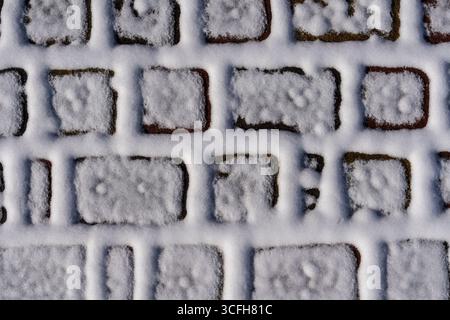 Weißer Schnee auf den Pflasterplatten, bedeckt mit einer dünnen Schicht von gefallenem weißem Schnee, Nahaufnahme, Ansicht von oben Stockfoto