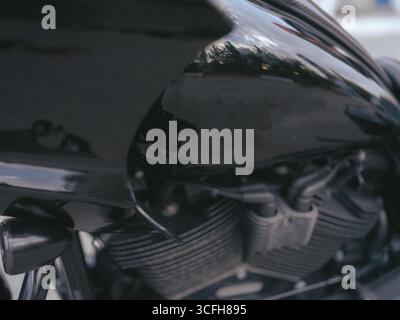 Nahaufnahme eines schwarzen Motorrads. Detaillierte Aufnahme, die die Seite des Kraftstofftanks mit Motor und Metallteilen zeigt. Konzept von Leistung, Geschwindigkeit, Straßenleben. Stockfoto