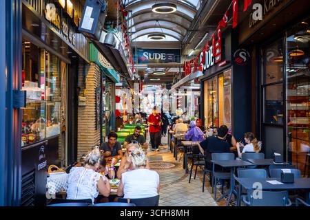 Menschen sitzen an Tischen und genießen Essen auf einem überdachten türkischen Straßenmarkt mit Restaurants und Cafés in Izmit, Kocaeli, Turkiye, am 21. August 202 Stockfoto
