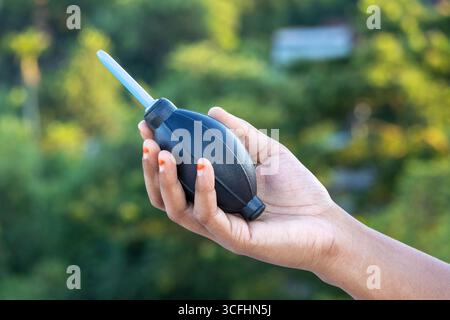 Eine Frau, die einen Staubreiniger mit einer Gummigebläse hält. Dieses Werkzeug ist ideal für die Reinigung von Kameras, Objektiven, Filtern, Musikinstrumenten, Computern, Stockfoto