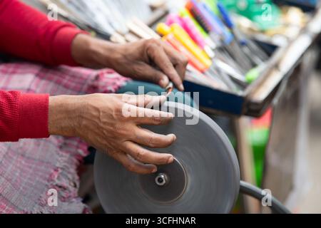 Schärfmesser Klinge auf Einem Schleifstein, indischer Messerschärfer bei der Arbeit, Rad über Pedale angetrieben, Kultur Indiens Stockfoto