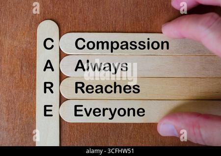 Holzstab Akronym PFLEGE betont Mitgefühl, Empathie, Inklusion, Vielfalt, Freundlichkeit, und Menschlichkeit in Teamwork-Werten Stockfoto