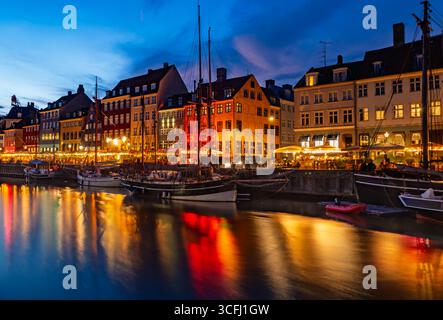 Nächtlicher Blick auf den Nyhavn-Damm in Kopenhagen, Dänemark, Yachten, Reflexionen auf dem Wasser, mit Lichtern beleuchtete Architektur Stockfoto