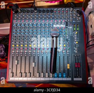 Professioneller Audio-Mixer mit Mikrofon im Casino, Nahaufnahme des Soundboards und Bedienelemente zur Hervorhebung der Musiktechnik und Unterhaltungsausstattung. Stockfoto