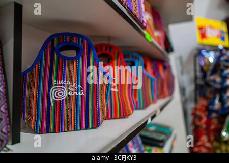 Farbenfrohe peruanische handgefertigte Taschen mit andenförmigen Textilmustern, die auf einem Regal in Cusco, Peru, ausgestellt sind und traditionelle Handwerkskunst und Kultur repräsentieren. Stockfoto