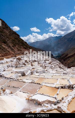 Maras Salzteiche in Cusco, Peru. Aus nächster Nähe sehen Sie Terrassen-Salzwasserbecken mit goldenen Tönen unter dem Himmel der Anden, historisches Inka-Kulturerbe. Stockfoto
