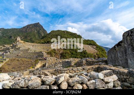 Steinmauern und landwirtschaftliche Terrassen von Machu Picchu in Cusco, Peru, mit Andenbergen im Hintergrund. Wahrzeichen des UNESCO-Weltkulturerbes. Stockfoto