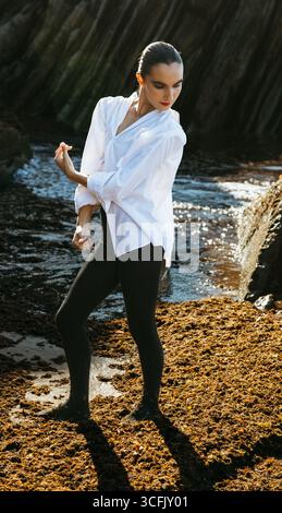 Ganzkörperaufnahme einer jungen Frau, die am Meer Flamenco tanzt, in künstlerischer Pose aufgenommen. Stockfoto