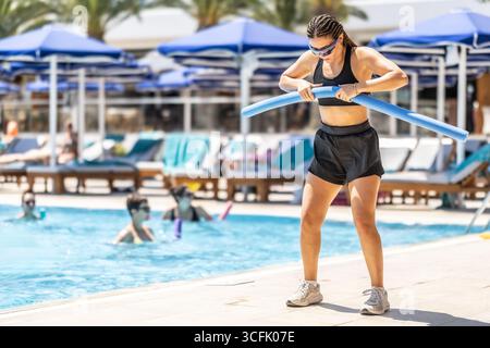 Eine junge weibliche Sportanimatorin macht Wassergymnastik für Menschen im Pool eines Hotelresorts. Stockfoto