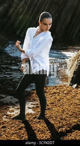 Ganzkörperaufnahme einer jungen Frau, die am Meer Flamenco tanzt, in künstlerischer Pose aufgenommen. Stockfoto