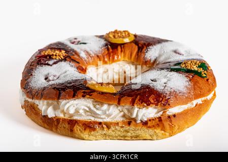 Roscon de Reyes gefüllt mit Creme auf weißem Hintergrund, ein süßes Teigbrötchen mit kandierten Früchten. Stockfoto