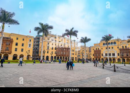 Plaza Mayor von Lima Peru mit gelben Kolonialgebäuden, Holzbalkonen, Palmen und Menschen, die auf dem historischen Platz spazieren gehen. Stockfoto