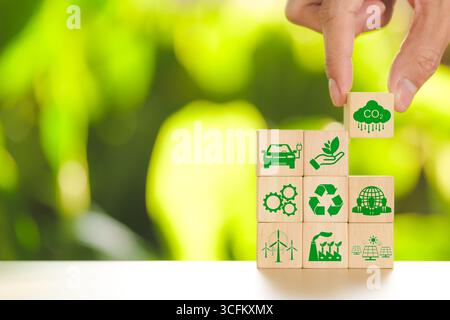 CO2-Fußabdruck-Konzept. Handgefertigter Holzwürfel mit Kohlenstoffreduzierung und grünem Symbol auf Naturhintergrund. Null-CO2-neutral, CO2-Emissionen, Stockfoto