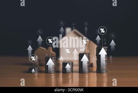 Immobilieninvestitionen und Finanzwachstumskonzept. Ein konzeptionelles Bild eines Miniaturhauses neben aufsteigenden Münzstapeln. Stockfoto