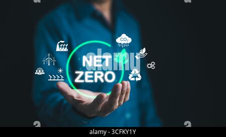 Nettonemissionskonzept. Mann hält sich an Symbole zur CO2-Reduktion. CO2-Bilanz, CO2-neutral, CO2-Neutralität, nachhaltige Energie, Klima Stockfoto