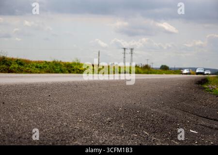 Flacher Blick auf die Landstraße mit Autos, die unter stimmungsvollem Himmel fahren Stockfoto