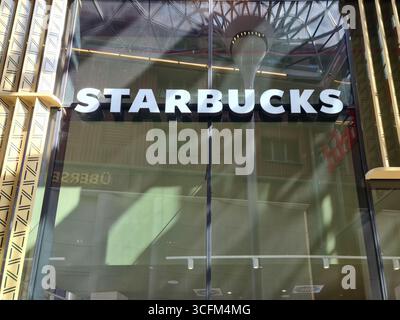 Hamburg, Deutschland - 23. August 2025: Das Starbucks-Logo auf einer Glasfassade spiegelt die städtische Umgebung Hamburgs wider Stockfoto