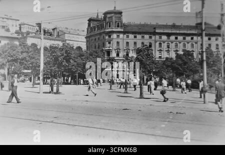 Ein altes Foto von der Rijeka Promenade und dem Continental Hotel, dem ältesten Hotel in Rijeka. Das Foto zeigt zahlreiche Passanten in Sommerkleidung, die durch die von Bäumen gesäumte Allee vor dem Hotel spazieren. 1953. Stockfoto