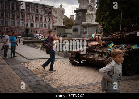 Kiew, Ukraine. August 2025. Ein Mann fotografiert seinen Sohn, der auf einem zerstörten Panzer posiert, während er während der Veranstaltung eine grüne Vyshyvanka trägt. Die Ukrainer gingen auf die Straßen der Hauptstadt, um den Flaggentag zu feiern. Sie trugen ihre besten Vyshyvankas (traditionelle bestickte Hemden, ein nationales Symbol). (Foto: Ximena Borrazas/SOPA Images/SIPA USA) Credit: SIPA USA/Alamy Live News Stockfoto