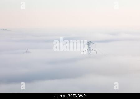 Im Nebel ist ein Stromleitungsturm zu sehen Stockfoto