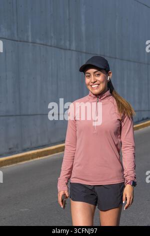Die junge Latina lächelt und geht draußen in Sportbekleidung Stockfoto