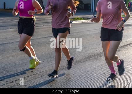 Drei nicht erkennbare junge Latina-Frauen laufen draußen in lässiger Sportbekleidung Stockfoto