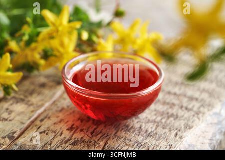 Rotes Öl aus St.. Johanniskraut blüht in einer Glasschale Stockfoto