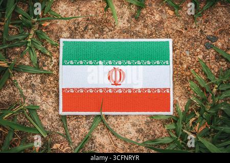 Umweltfreundliche iranische Flaggenstickerei auf Naturstein mit grünen Blättern im Wald symbolisiert den Tag der Erde, das Bewusstsein für den Klimawandel und die Nachhaltigkeit. Stockfoto