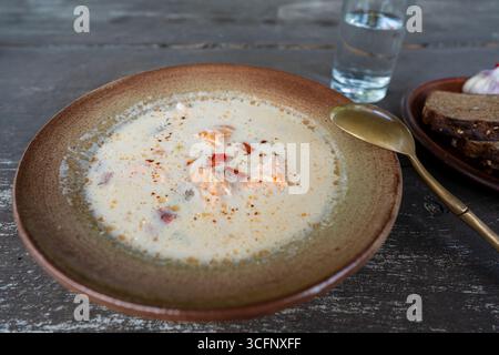Lachssuppe mit Sahne, Kartoffeln, Karotten, Paprika und Kräutern in einer Schüssel auf dem Tisch, Nahaufnahme Stockfoto