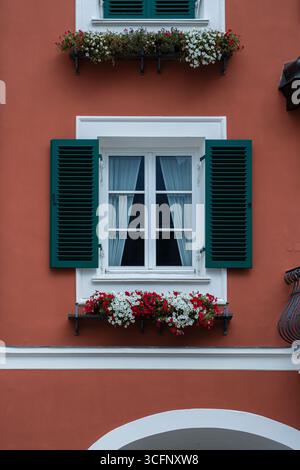 Fenster an der roten Wandfassade mit offenen grünen klassischen Fensterläden, Österreich, Nahaufnahme Stockfoto
